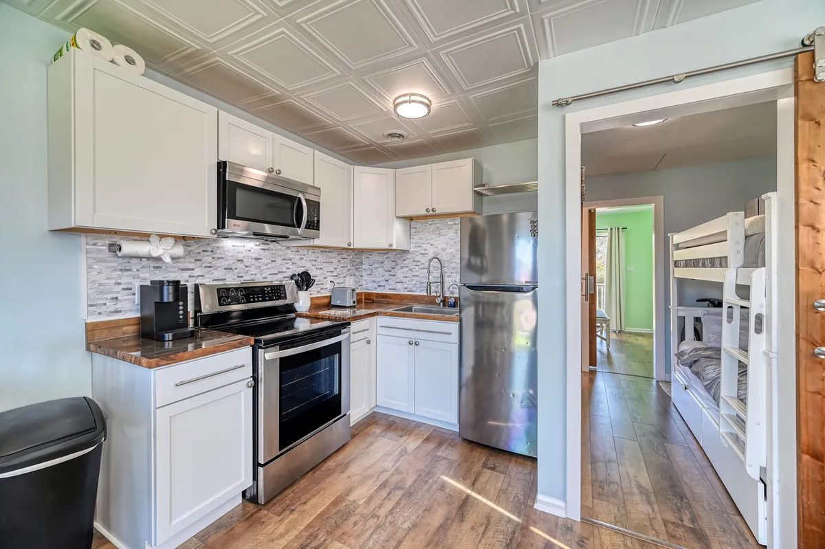 A cozy, multi-functional living area with built-in wooden bunk beds, modern kitchen appliances, and a compact dining space. The layout is efficient, maximizing space for families or groups to gather, relax, and enjoy meals together. The room exudes a welcoming vibe, perfect for short, spontaneous stays.