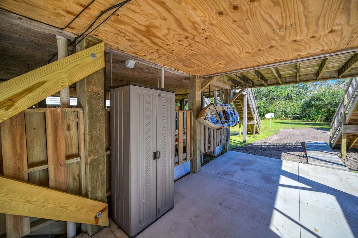 A bright and airy multi-use area featuring a storage cabinet, wooden stairs, and surfboards neatly placed, with a view of the outdoors through an open doorway. The space feels casual and ready for adventure, signaling easy transitions between indoor relaxation and outdoor exploration.