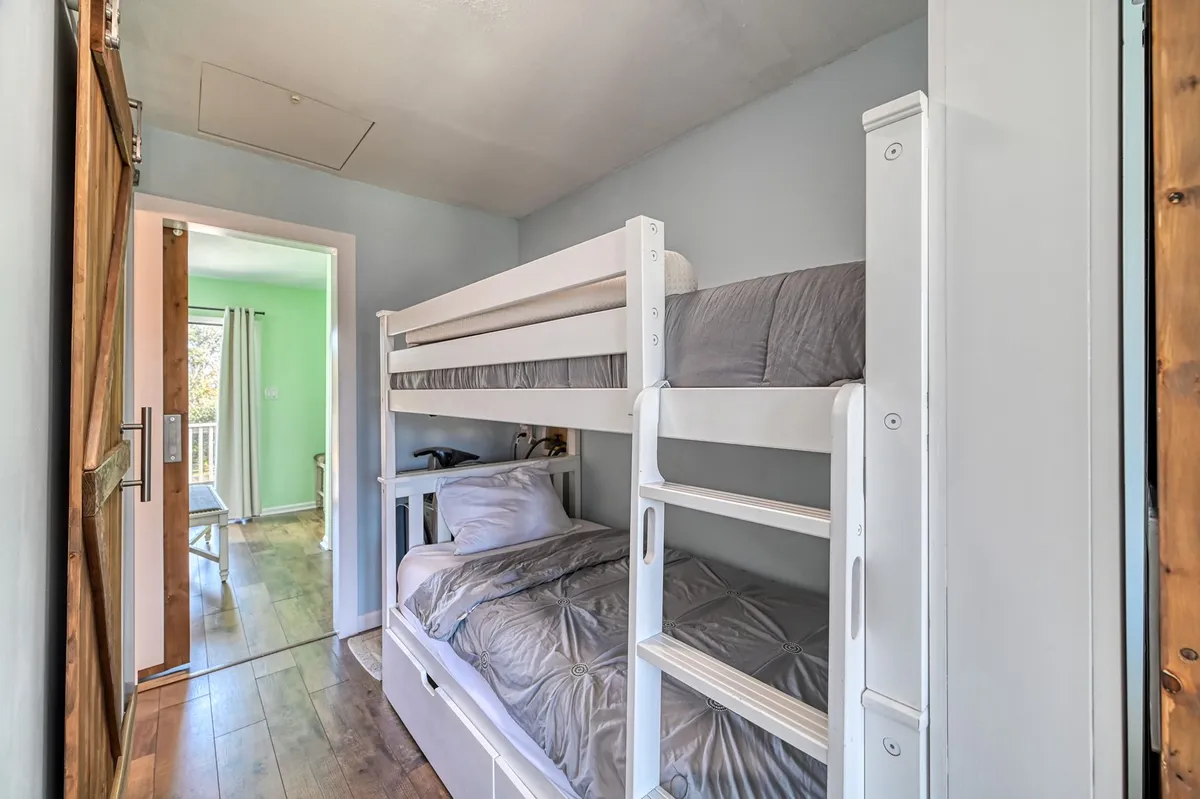 A playful and cozy hallway nook with built-in bunk beds is shown here, with the view extending through a doorway that suggests proximity to other living spaces. The mood is playful yet relaxed, making it suitable for children or extra guests.