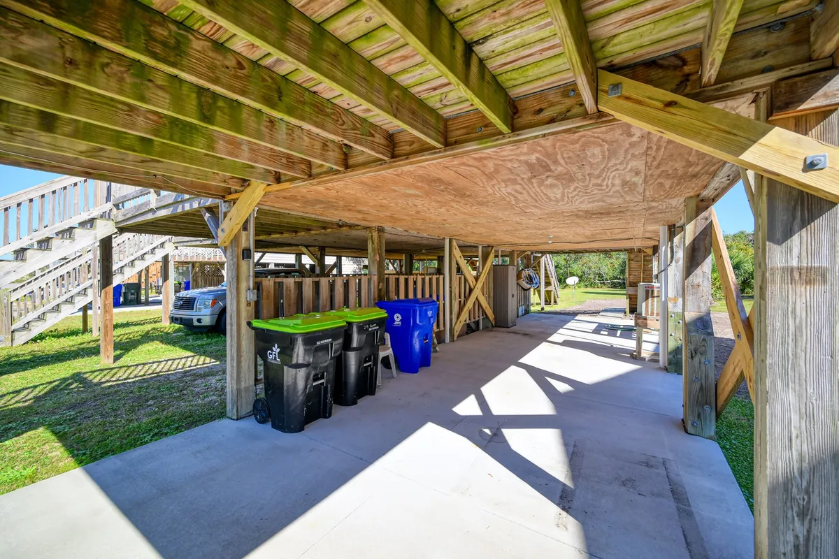 A covered parking area with a wooden structure, garbage bins, and concrete flooring. The space is practical, well-maintained, and hints at convenience for residents, also tying into the sense of community.