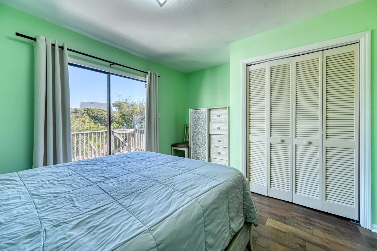 This image depicts a serene queen bedroom, bathed in natural light, with a large bed as the focal point. Accents such as a wardrobe and decorative mirror add a touch of elegance. The calm and refreshing mood is enhanced by soft linens and carefully chosen decor, suggesting a comfortable retreat ideal for relaxation and recharging.